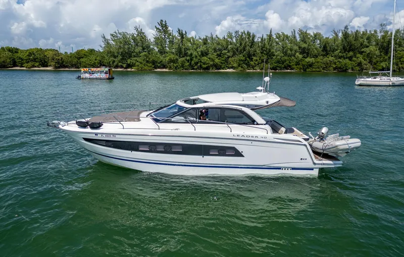 Slide: The Image of 2019 Jeanneau Leader 40 yacht cruising on a serene lake with lush greenery. - 19