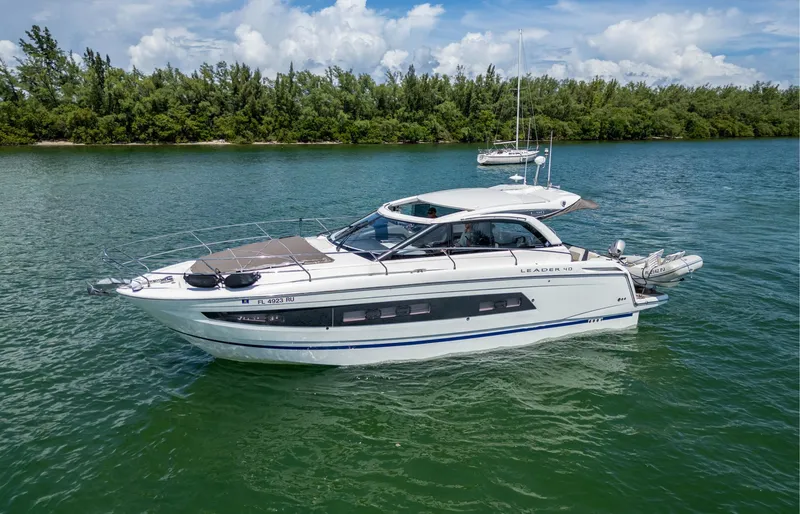 Slide: The Image of 2019 Jeanneau Leader 40 yacht cruising on a serene lake with lush greenery. - 20