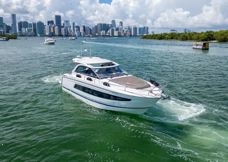 Slide: The Image of 2019 Jeanneau Leader 40 yacht cruising near city skyline and lush greenery. - 7