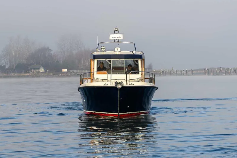 Slide: The Image of 2020 Targa 32 boat cruising on calm water with misty shoreline background. - 2