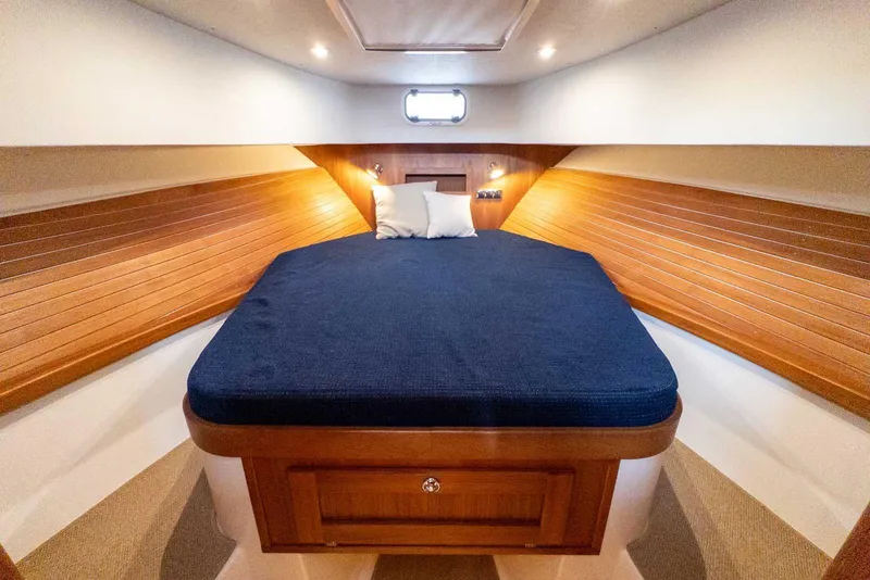 Slide: The Image of Cozy cabin interior of 2020 Targa 32 boat with wooden paneling and blue bedding. - 30