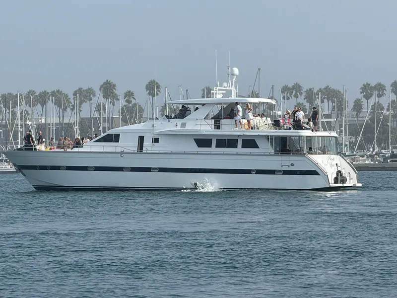 The Image of 1990 Versilcraft Challenger Motor Yacht cruising near a marina with palm trees in the background. - 0