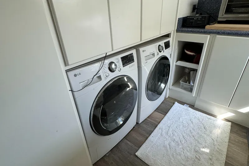 Slide: The Image of Laundry area with LG washer and dryer, white cabinets, and a rug on wooden floor. - 32