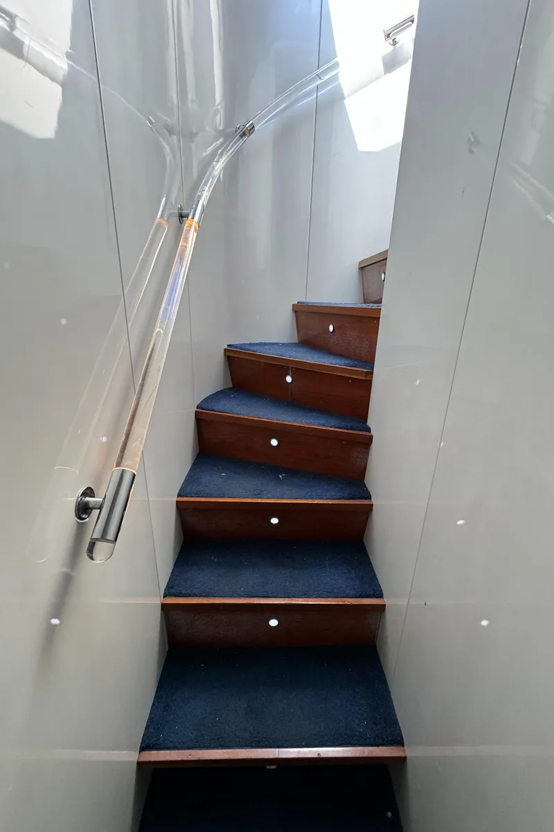 Slide: The Image of Staircase inside 1990 Versilcraft Challenger Motor Yacht with blue carpet and wooden steps. - 35