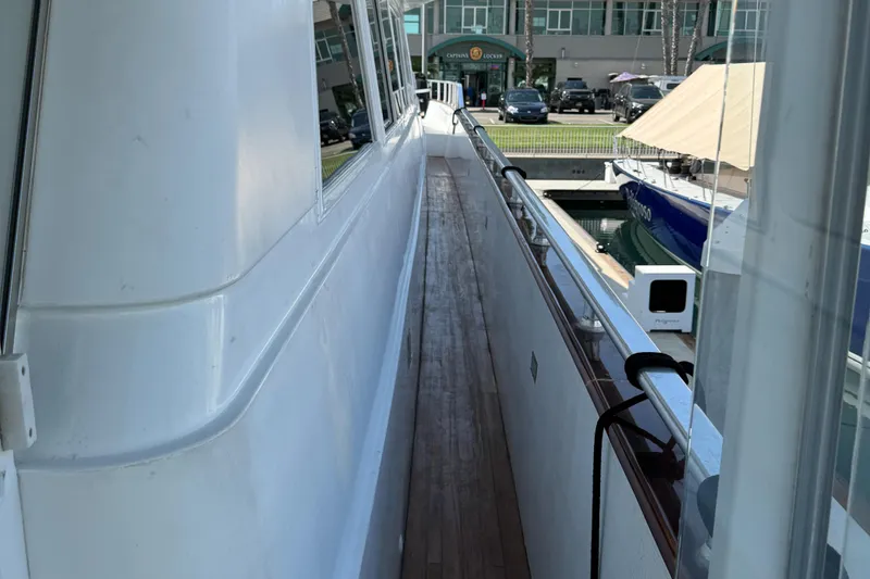 Slide: The Image of Side deck of 1990 Versilcraft Challenger Motor Yacht, featuring sleek white exterior and wooden walkway. - 7