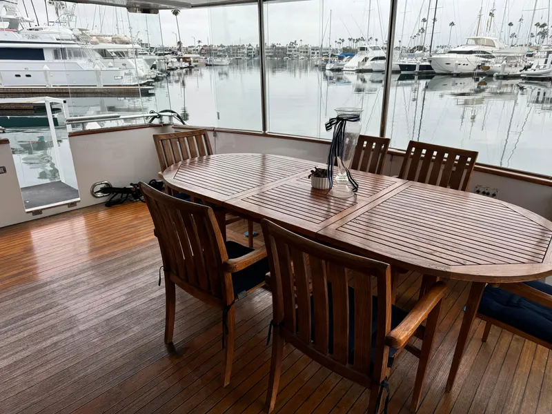 Slide: The Image of 1990 Versilcraft Challenger Motor Yacht with wooden deck and dining area in marina setting. - 9