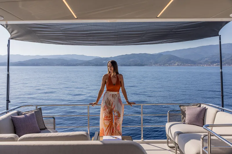 Slide: The Image of Woman enjoying view on 2025 Absolute 56 FLY yacht deck, surrounded by ocean and mountains. - 17