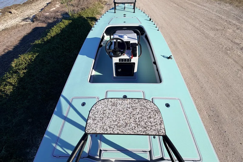 Slide: The Image of 2021 Chittum Skiffs Islamorada 18, light blue deck, steering console, parked on dirt road. - 77