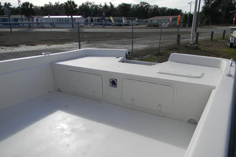 Slide: The Image of 2026 Carolina Skiff E24 DLX CC boat interior with storage compartments, parked outdoors. - 3