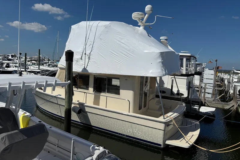 The Image of 2006 Mainship 34 Trawler cruising near waterfront homes. - 0