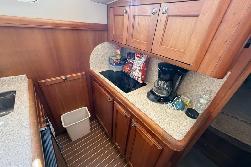Slide: The Image of 2006 Mainship 34 Trawler kitchen with microwave, sink, and wooden cabinetry. - 21