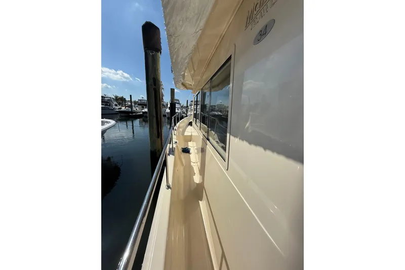Slide: The Image of 2006 Mainship 34 Trawler docked, covered with white tarp, sunny marina setting. - 4