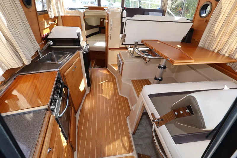 Slide: The Image of Interior of 2015 Ranger Tugs R-29 S, featuring wood finishes and compact kitchen area. - 14