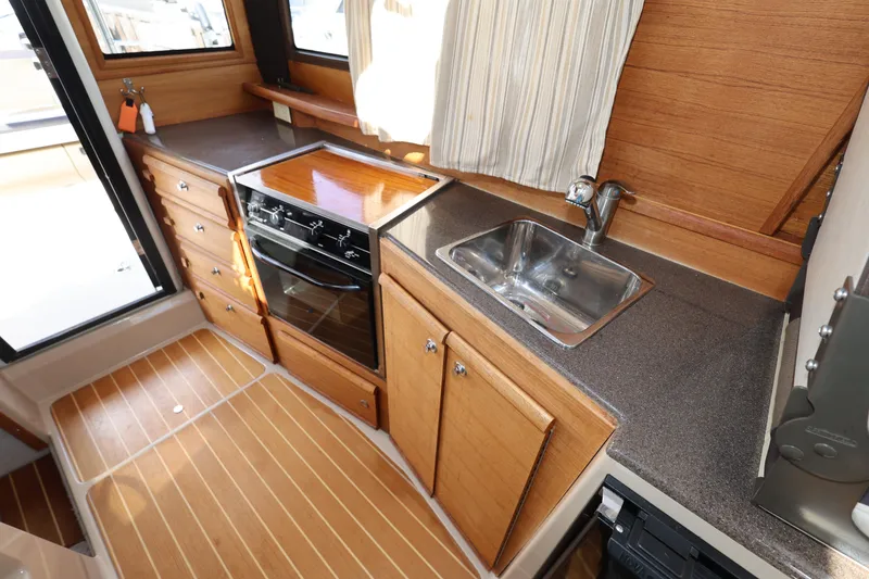 Slide: The Image of 2015 Ranger Tugs R-29 S interior kitchen with wood cabinetry and stainless steel sink. - 15
