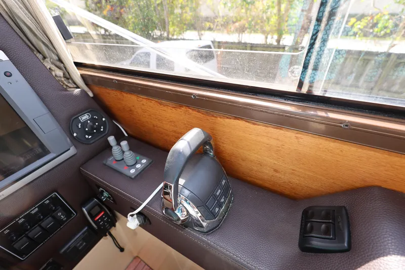 Slide: The Image of 2015 Ranger Tugs R-29 S helm controls with joystick and throttle, featuring wood and leather accents. - 21