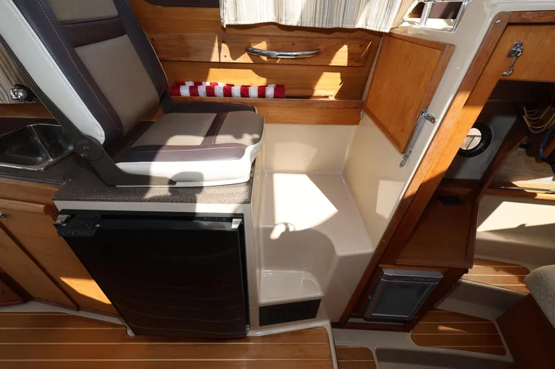 Slide: The Image of 2015 Ranger Tugs R-29 S interior with seating, wood accents, and compact kitchenette. - 23