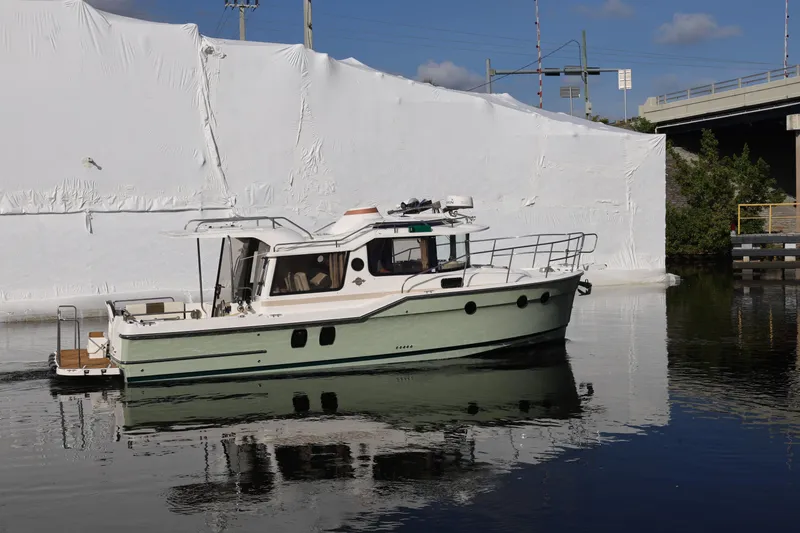 Slide: The Image of 2015 Ranger Tugs R-29 S boat on calm water near a white structure. - 3