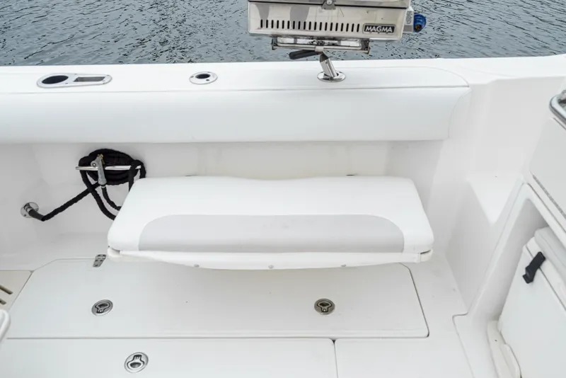 Slide: The Image of 2008 Boston Whaler 345 Conquest boat seating area with white cushioned bench. - 23