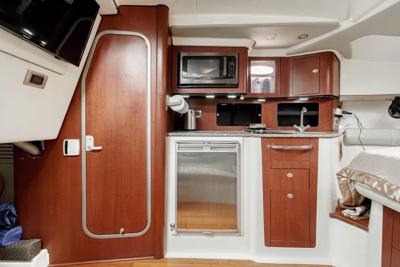 Slide: The Image of 2008 Boston Whaler 345 Conquest cabin kitchen with microwave, fridge, and wooden cabinetry. - 46