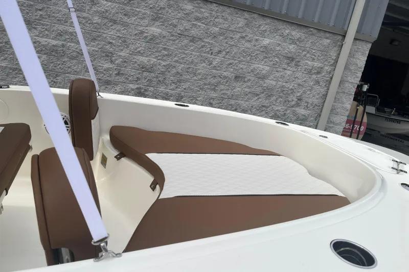 Slide: The Image of 2026 Pioneer 180 Sportfish boat interior with brown and white seating, docked near a gray wall. - 11