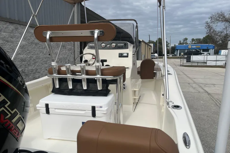 Slide: The Image of 2026 Pioneer 180 Sportfish boat interior with seating and console, parked outdoors. - 18
