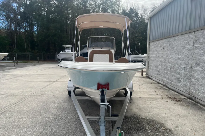 Slide: The Image of 2026 Pioneer 180 Sportfish boat on trailer, parked outdoors near a building. - 7