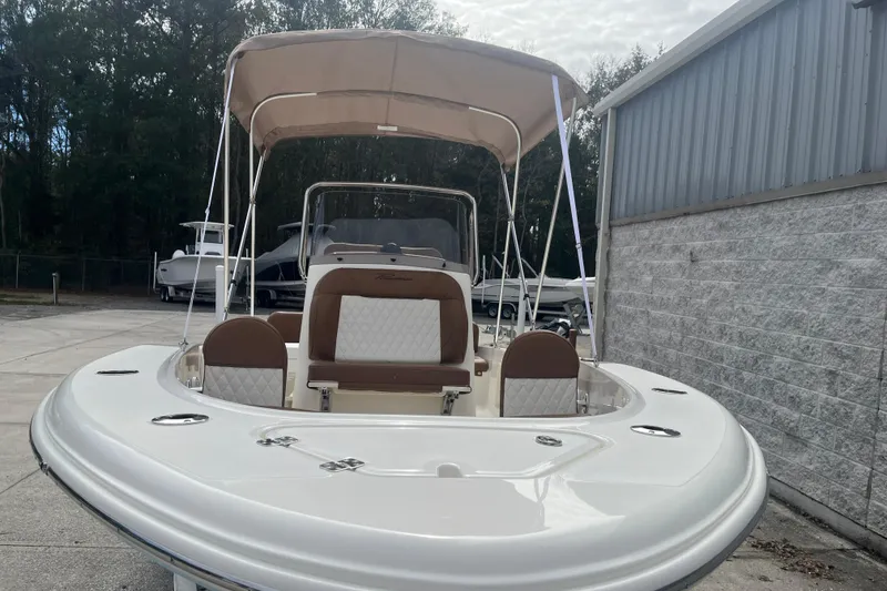 Slide: The Image of 2026 Pioneer 180 Sportfish boat with canopy, parked outdoors near a building. - 9