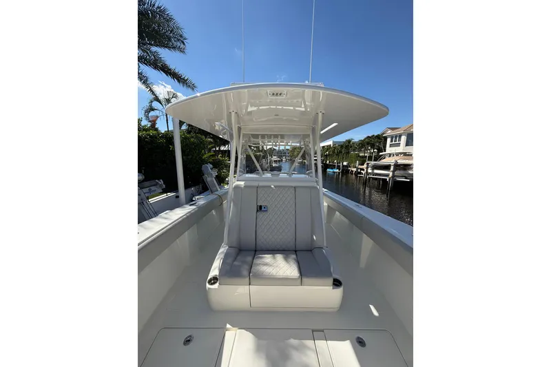 Slide: The Image of 2022 SeaVee 370Z boat interior with seating, docked by waterfront homes. - 13