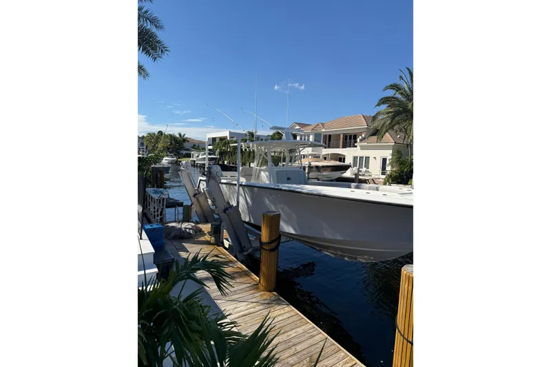 Slide: The Image of 2022 SeaVee 370Z boat docked near waterfront homes, surrounded by palm trees. - 2