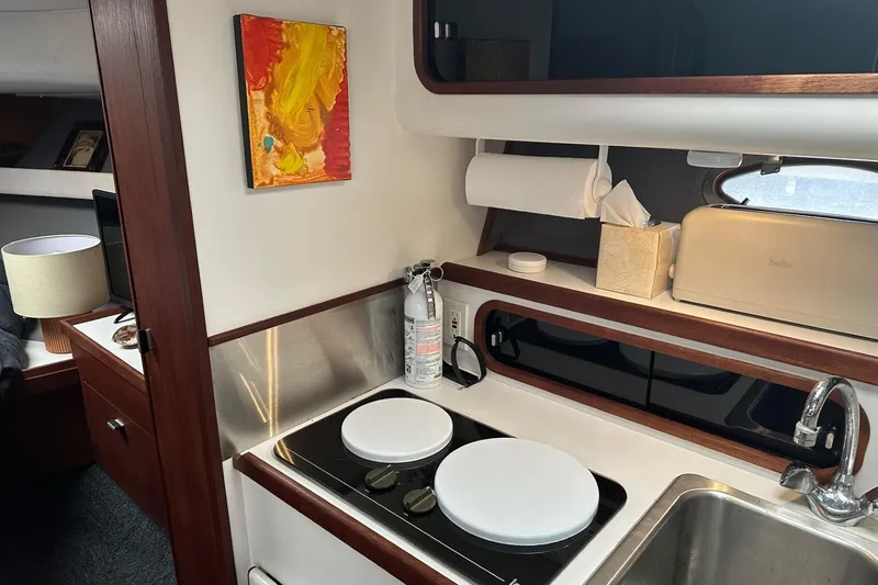 Slide: The Image of 1989 Tiara Yachts 3100 Flybridge interior kitchen with stove, sink, and colorful wall art. - 10