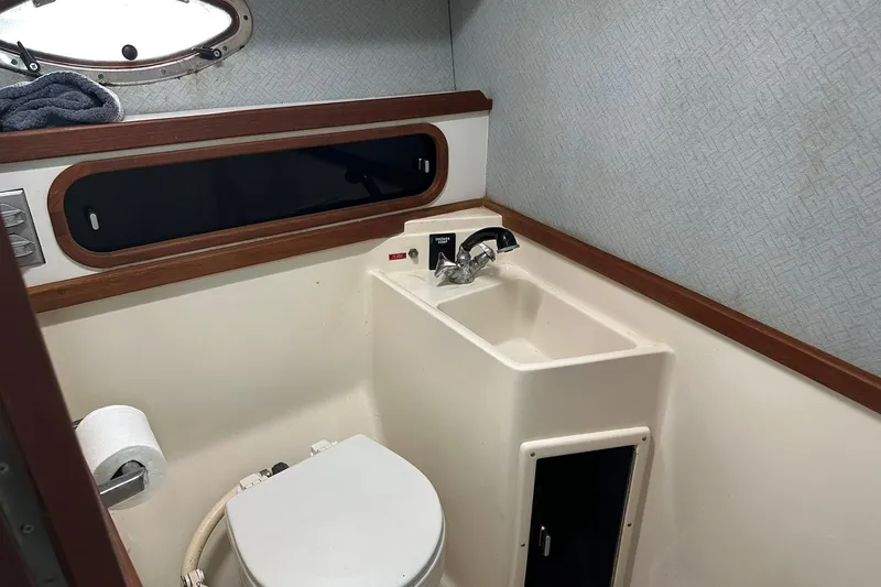 Slide: The Image of 1989 Tiara Yachts 3100 Flybridge bathroom with sink, toilet, and porthole window. - 5