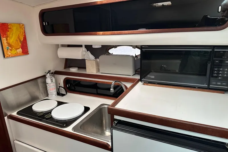 Slide: The Image of 1989 Tiara Yachts 3100 Flybridge kitchen with stove, sink, microwave, and storage. - 9