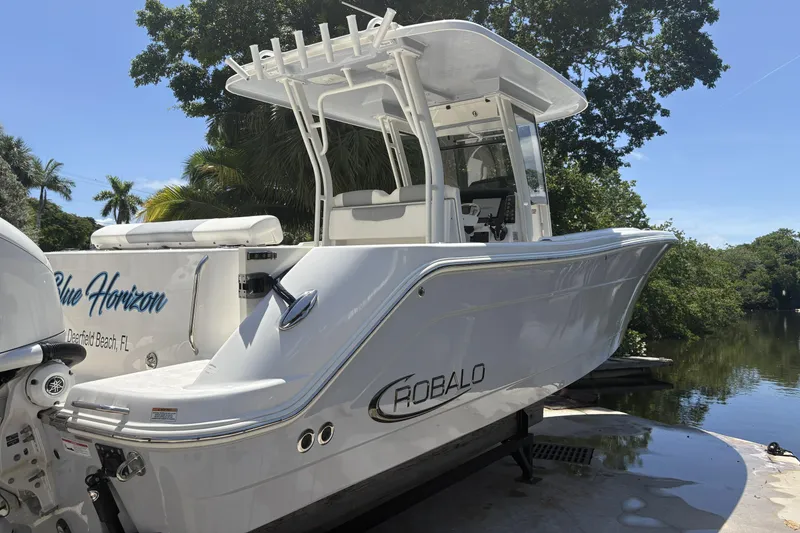 Slide: The Image of 2023 Robalo R302 Center Console boat docked near lush greenery. - 4