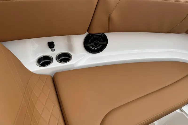 Slide: The Image of 2026 Chaparral 250 OSX interior with tan leather seats, cup holders, and speaker. - 11
