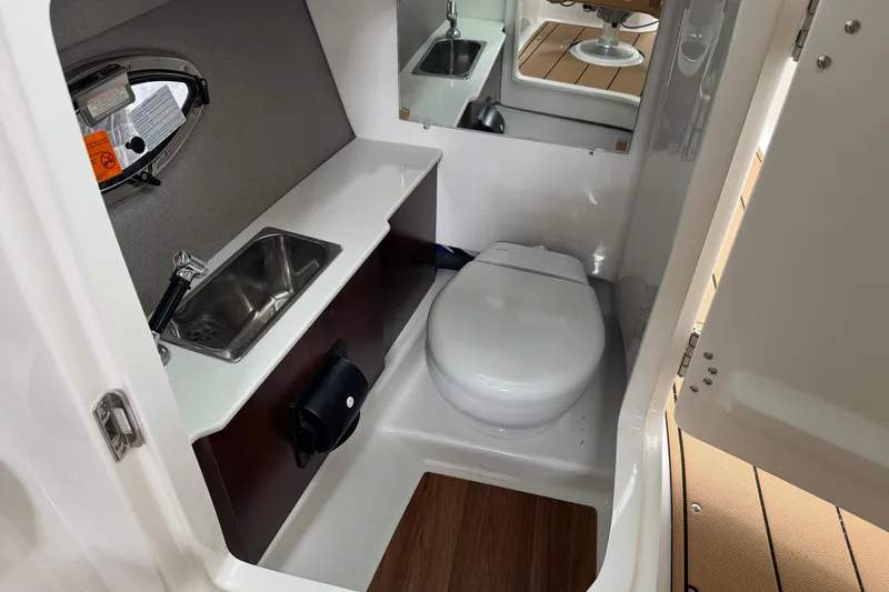 Slide: The Image of 2026 Chaparral 250 OSX boat interior with compact bathroom, sink, and toilet. - 20