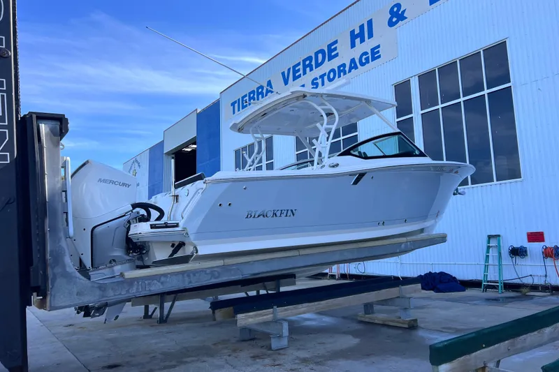 Slide: The Image of 2022 Blackfin 272 DC boat on lift at storage facility, featuring Mercury engines. - 101