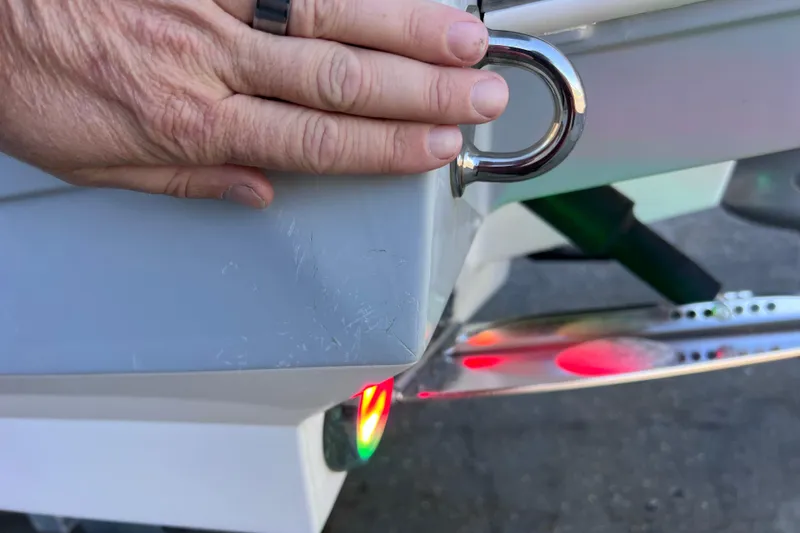 Slide: The Image of Hand inspecting 2022 Blackfin 272 DC boat with visible scratches and navigation light. - 107