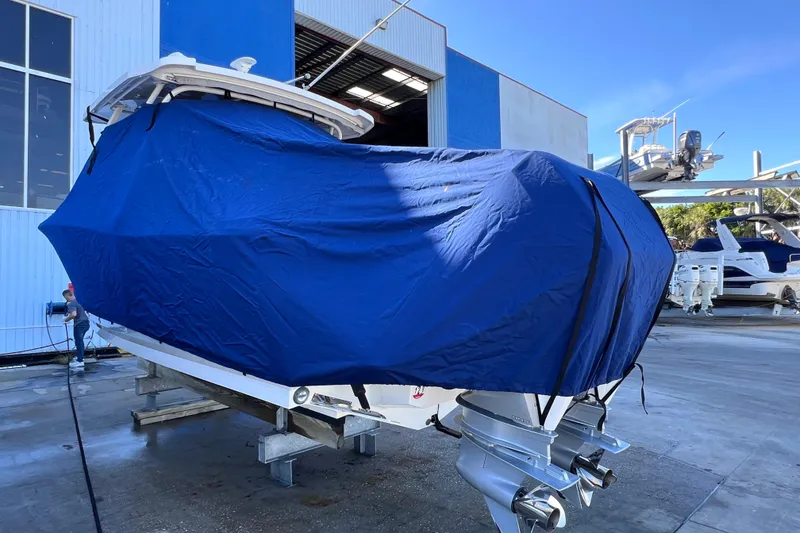 Slide: The Image of 2022 Blackfin 272 DC boat covered with blue tarp in marina setting. - 15
