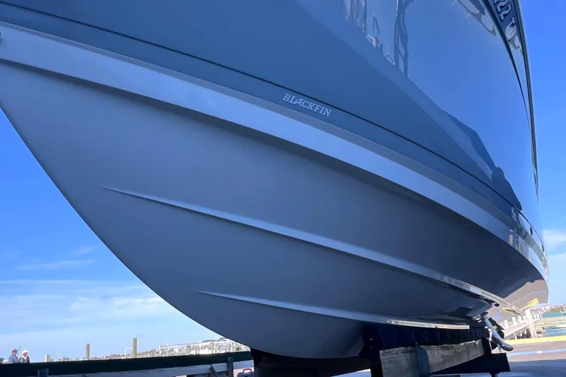 Slide: The Image of 2022 Blackfin 272 DC boat hull, sleek design under clear blue sky. - 23