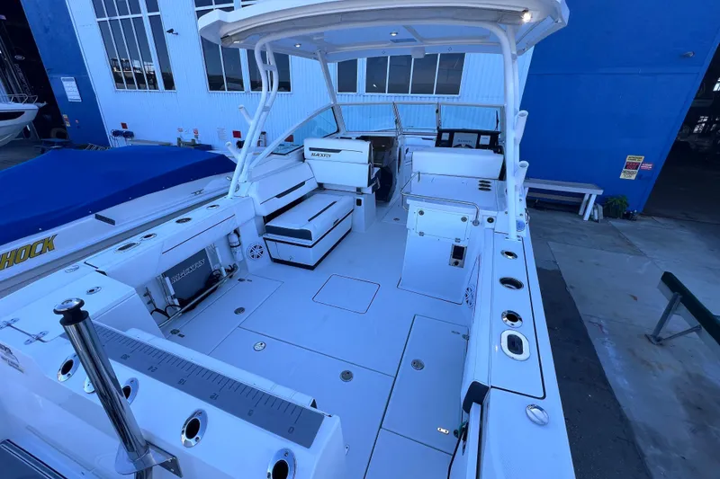 Slide: The Image of 2022 Blackfin 272 DC boat interior with seating and storage, docked near a blue building. - 32
