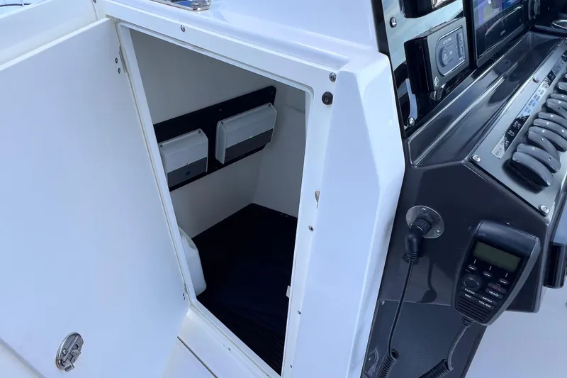 Slide: The Image of 2022 Blackfin 272 DC boat interior with open storage compartment and control panel. - 82