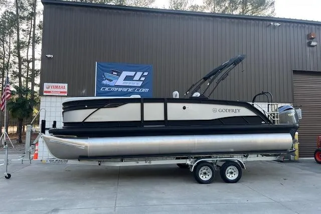 Slide: The Image of 2026 Godfrey Monaco 235 SFLC pontoon boat on trailer outside a marine dealership. - 4