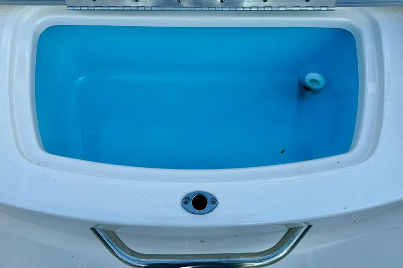 Slide: The Image of 2024 Chaparral 19 SSi OB boat livewell with blue interior and stainless steel handle. - 48