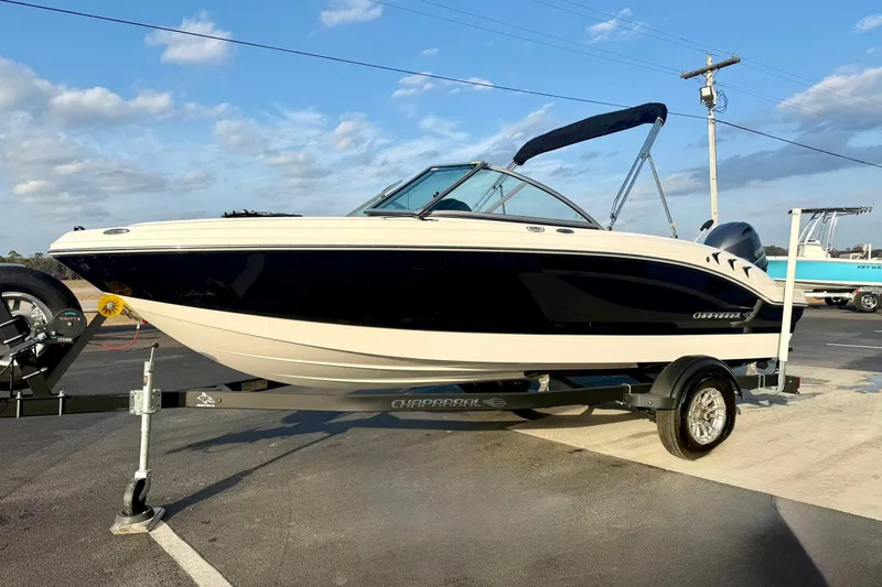 Slide: The Image of 2024 Chaparral 19 SSi OB boat on trailer, parked outdoors under blue sky. - 6