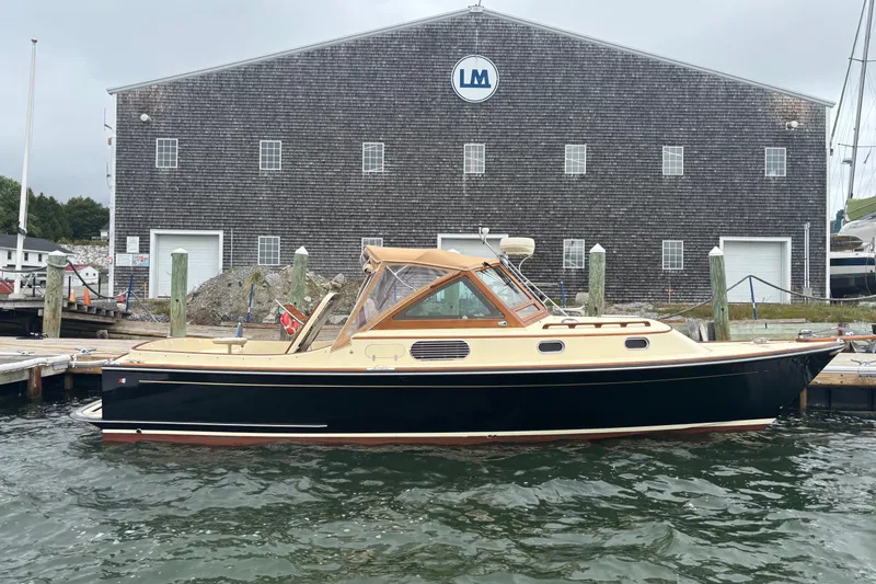 Slide: The Image of 2005 C.W. Hood Katama 30 boat docked near a large wooden building. - 1