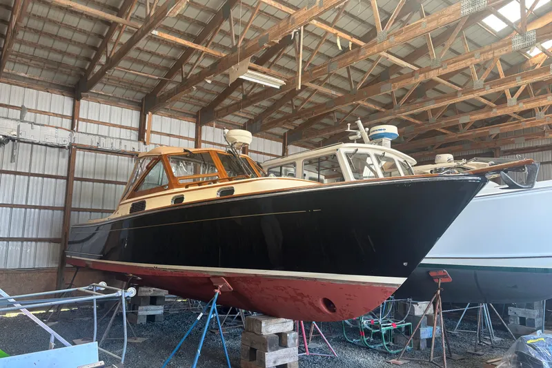 Slide: The Image of 2005 C.W. Hood Katama 30 boat in storage, wooden interior, black hull, red bottom. - 14