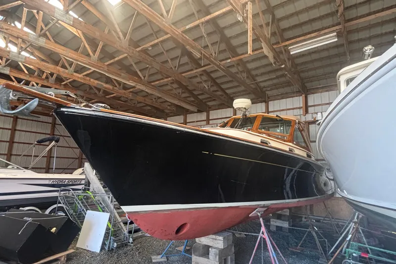 Slide: The Image of 2005 C.W. Hood Katama 30 boat in storage, black hull, wooden cabin, indoor facility. - 15