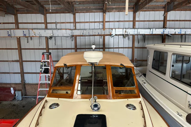 Slide: The Image of 2005 C.W. Hood Katama 30 boat in storage, with wooden cabin and nearby ladder. - 17