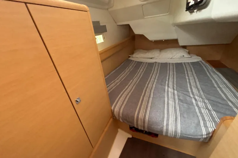 Slide: The Image of 2017 Jeanneau Sun Odyssey 389 cabin with striped bedding and wooden cabinetry. - 49