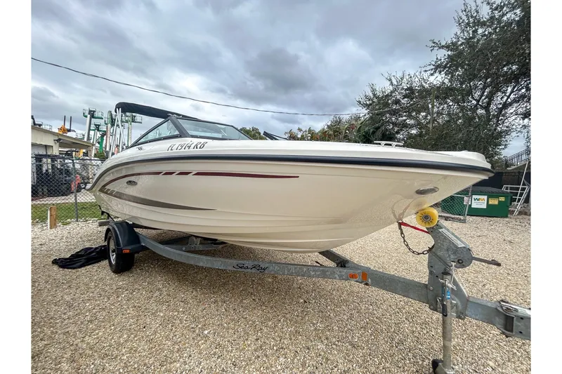 Slide: The Image of 2016 Searay 190 SPX boat on trailer, parked outdoors under cloudy sky. - 2